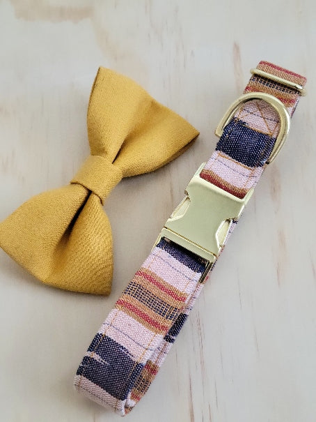 dog collar made from handwoven ikat fabric in a wide stripe pattern. deep navy with muted red and mustard yellow stripes with wide stripes of off-white background. Fabric handwoven by an artisan in Guatemala. Shown with shiny gold metal buckle. Collar has been paired with a solid, mustard yellow linen dog bow tie that coordinates the collar beautifully while maintaining a natural, boho appearance.