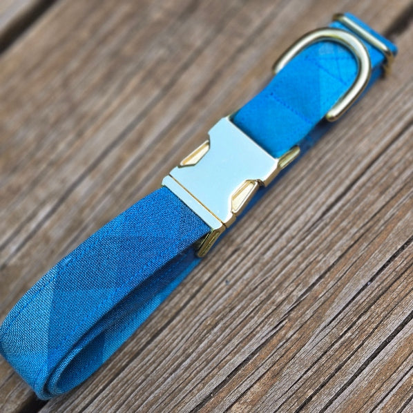 blue checker plaid in an ombre of colors ranging from bright sky blue, bright blue, to navy. Plaid is on the bias, with checks approximately 1" square.Collar made with yarn dyed woven cotton. Shown with shiny gold metal hardware.