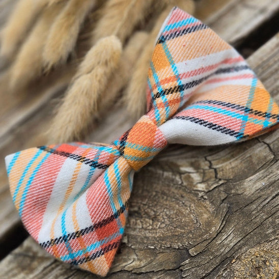 the perfect fall plaid dog accessory. with orange, yellow orange, complimentary turquoise, and black stripes on a white background. This bow tie is perfect for fall.