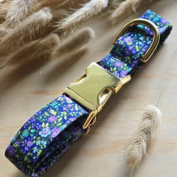 dainty floral dog collar with purple flowers, small pops of turquoise and bright lime green leaves, dark royal purple background. shown with shiny gold metal buckle