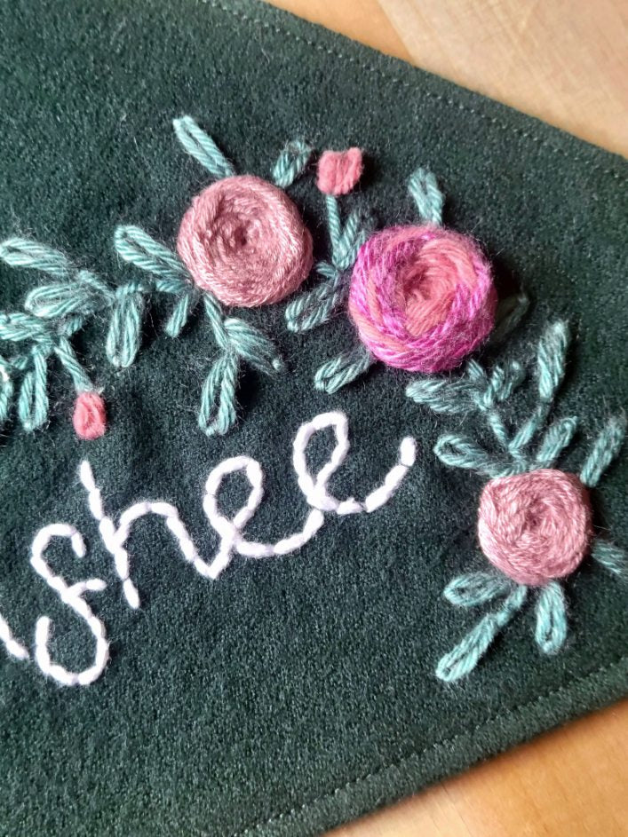 close up of intricate hand embroidered rosettes and greenery