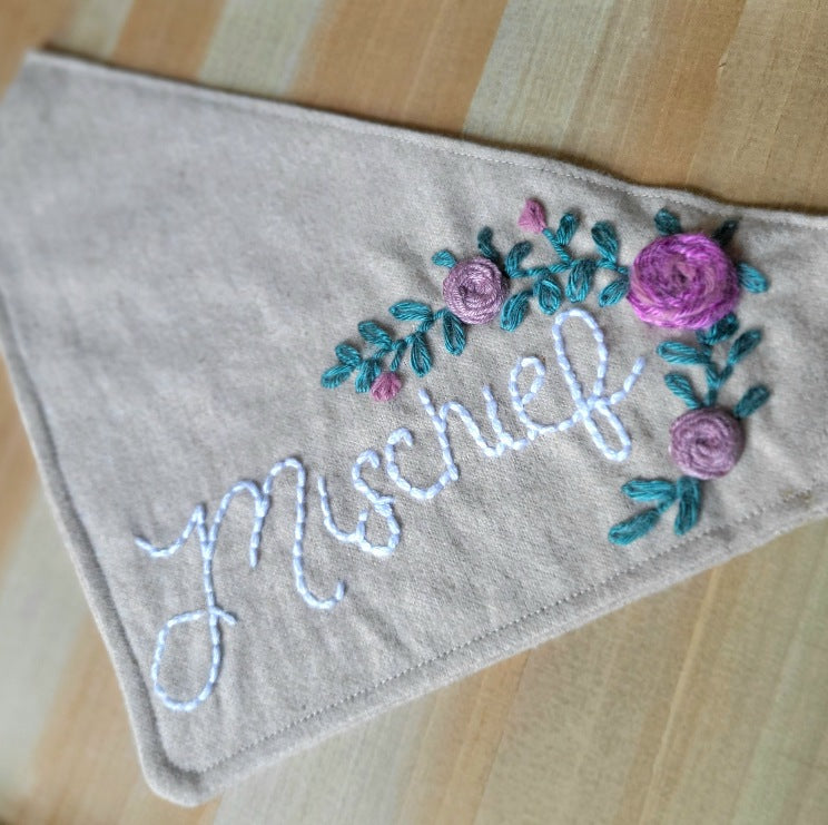 oatmeal colored dog bandana with hand embroidered rosettes and greenery, personalized with dogs name