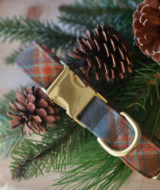 Handsome plaid flannel dog collar with high contrast. Plaid includes pops of orange, seafoam green, and ochre on a deep muted blueish green. Shown with gold metal buckle