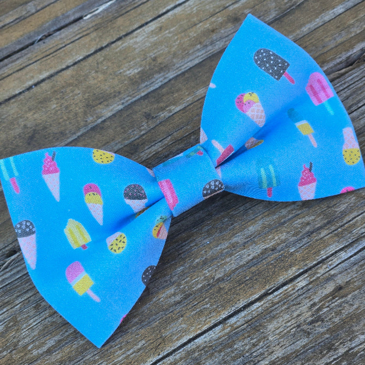Blue bow tie with ice cream and popsicle pattern on a wooden surface