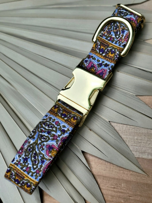 gorgeous dog collar made from vintage fabric, estimated to be from the 60s. Collar features jewel tones in pinks, olive green, purple, and orange on a sky blue background. Pattern is bohemian featuring elaborate floral design and paisley type pattern. Shown with shiny gold metal buckle. unique and handmade in kansas city