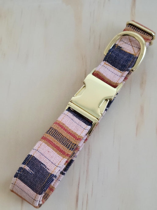 dog collar made from handwoven ikat fabric in a wide stripe pattern. deep navy with muted red and mustard yellow stripes with wide stripes of off-white background. Fabric handwoven by an artisan in Guatemala. Shown with shiny gold metal buckle