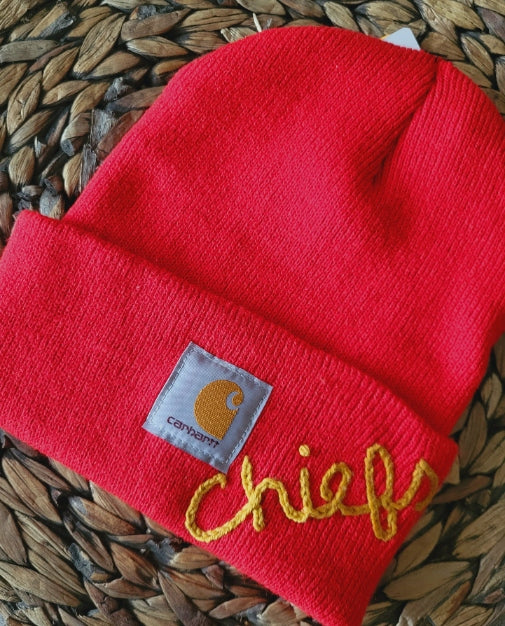red carhartt knit hat with hand embroidered chiefs in mustard yellow thread on hat brim. one size fits all