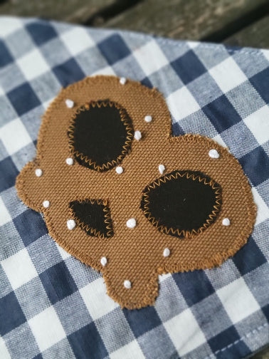 close up of hand appliqued pretzel with french knots for grains of salt