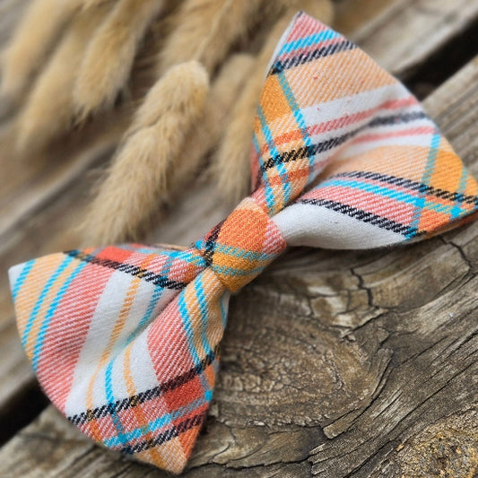 the perfect fall plaid dog accessory. with orange, yellow orange, complimentary turquoise, and black stripes on a white background. This bow tie is perfect for fall. 