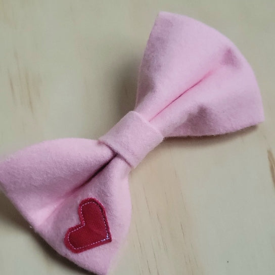 solid bubblegum pink cotton flannel fancy girl dog bow. small contrasting red heart appliqued on bottom left corner of bow 