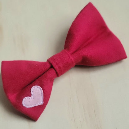 solid red cotton flannel dog bow tie, small contrasting bubblegum pink heart appliqued on bottom left corner of bow tie