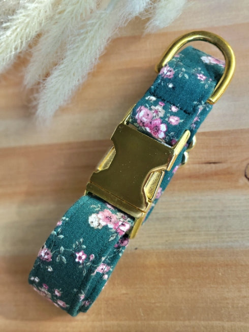 dog collar made from vintage fabric, likely from the 80s. Small pink and mauve dainty flowers on a dark green background. shown with shiny gold metal buckle